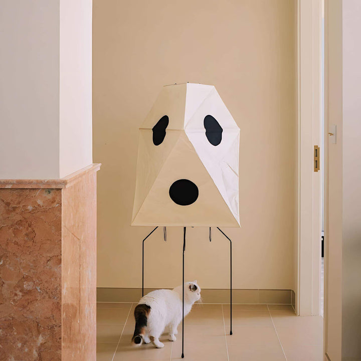 Unique white rice paper floor lamp shaped like a ghost, with a cat nearby in a minimalist interior.