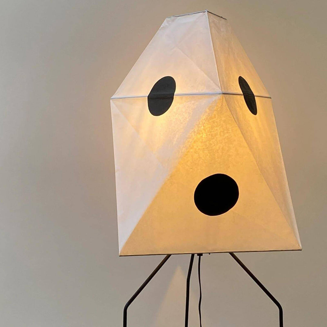 Akari UF3-Q white rice paper floor lamp with minimalist design, on tripod base, illuminating with soft light.