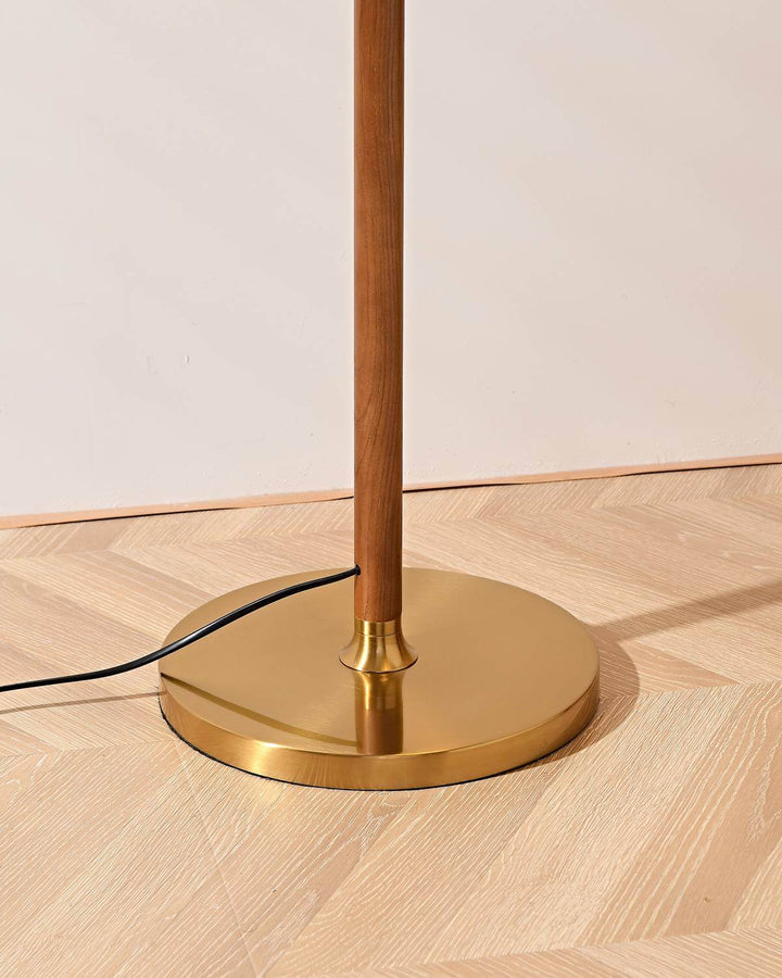Close-up of the base of the Nelke curved wooden floor lamp with a gold finish, perfect for minimalist decor.