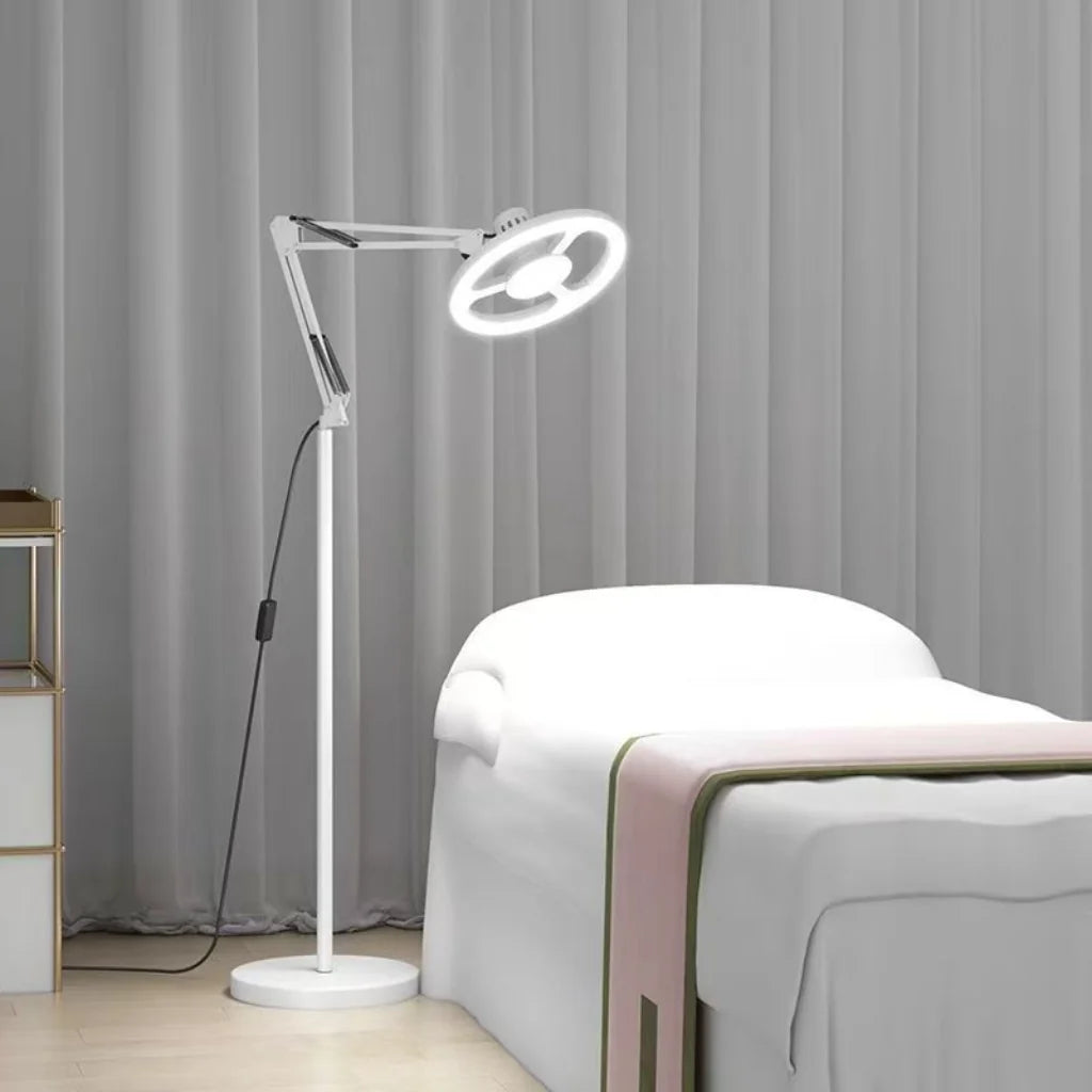 White Adjustable LED Ring Floor Lamp beside treatment bed