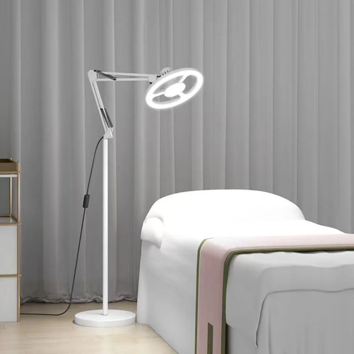 White Adjustable LED Ring Floor Lamp beside treatment bed