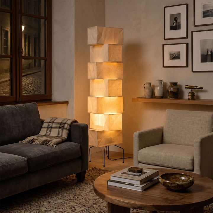 White Akari Paper Floor Lamp glowing beside a dark sofa in a living room