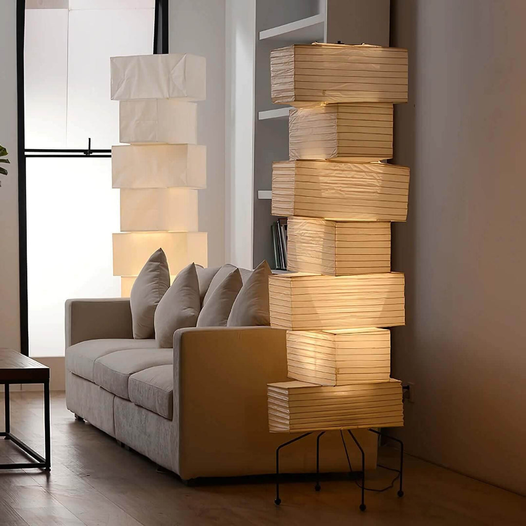 Two tall Akari rice paper floor lamps arranged around a white sofa in a contemporary living room