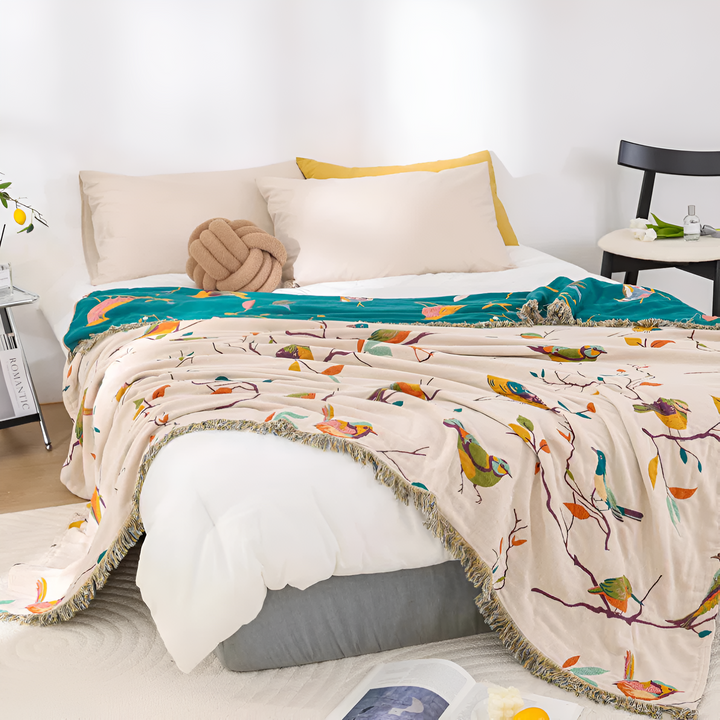 Boho Bird Print Cotton Throw layered on a bed with pillows