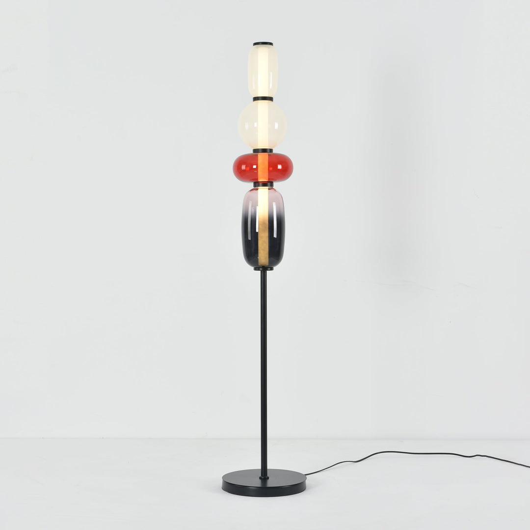 Illuminated Candied Model A Red glass floor lamp with a slim black stem and round base on a white background.