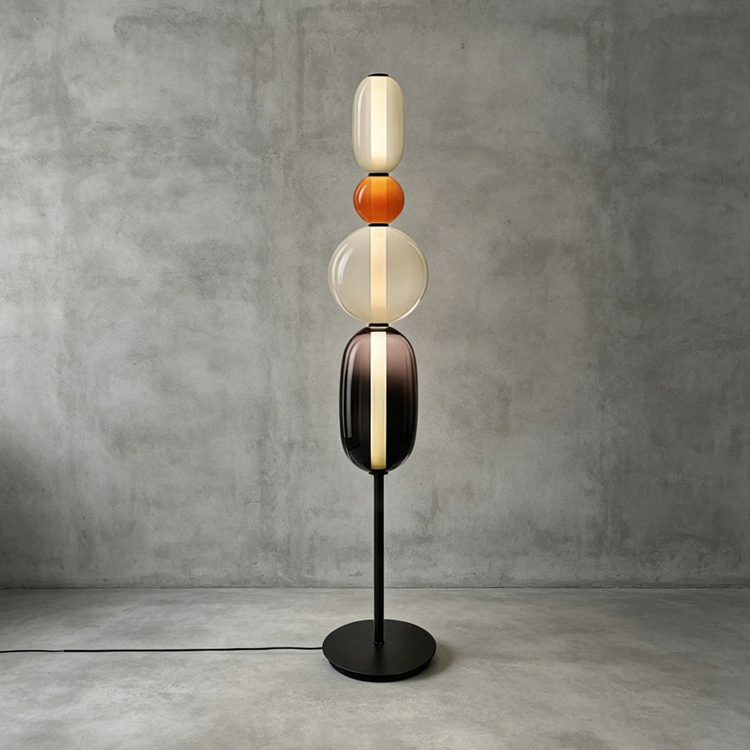 Tall Candied Model B Orange glass floor lamp with a warm vertical light and round black base.