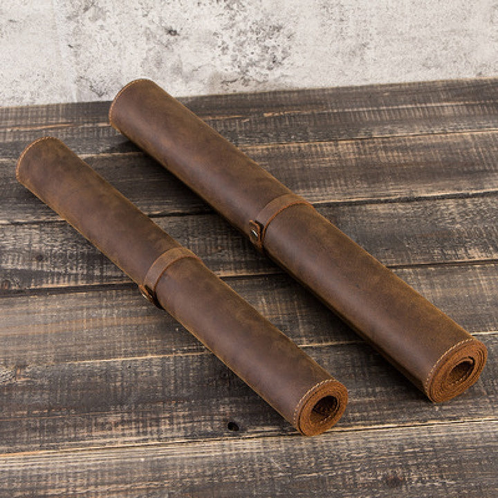 Rolled leather desk mats on a wooden surface