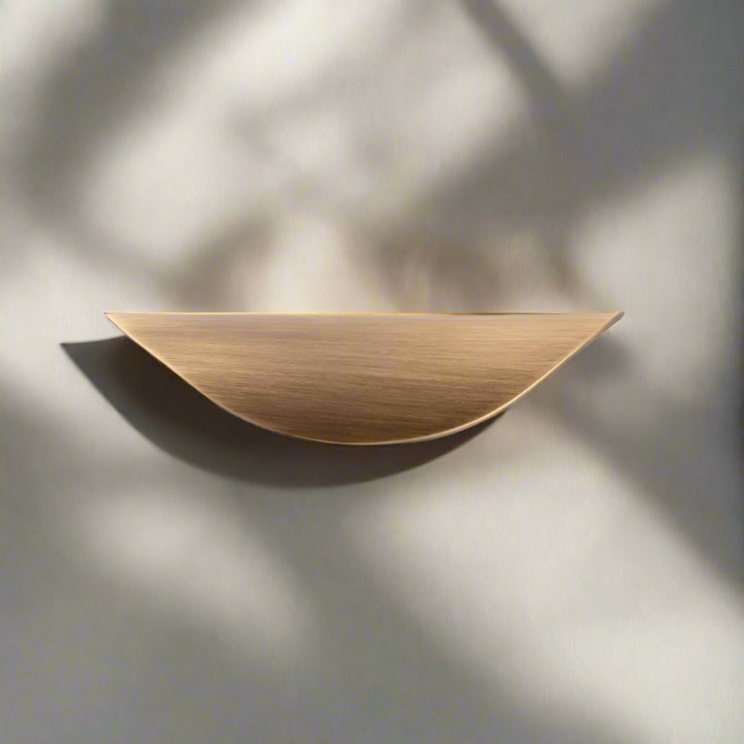 Crescent Brushed Brass Cabinet Pull on white drawer top view
