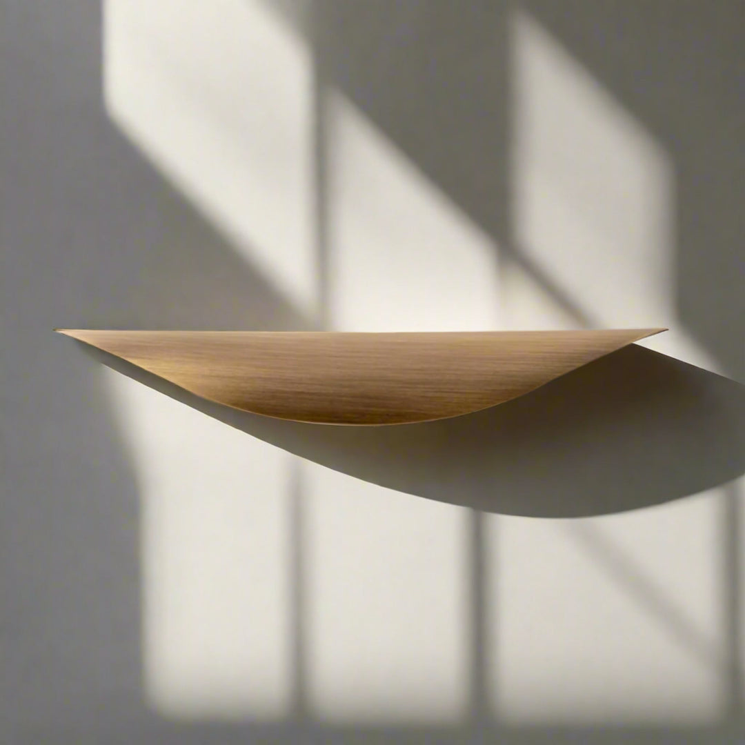 Crescent Brushed Brass Cabinet Pull on drawer front in sunlight