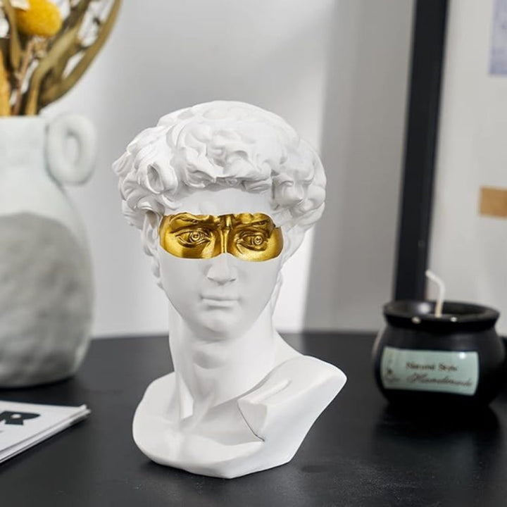 White David Bust Sculpture with gold eye mask on desk