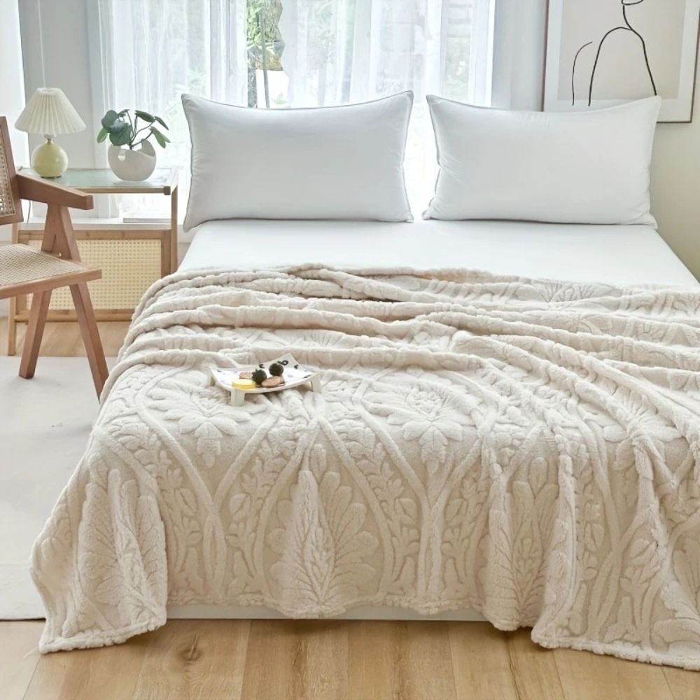 Sandstone Embossed Plush Fleece Throw draped on a bed
