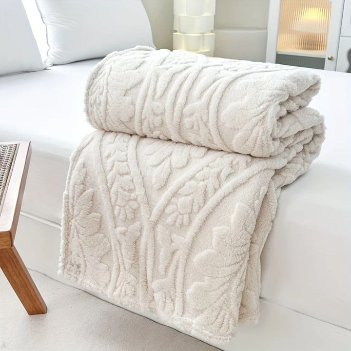 Ivory Cloud Embossed Plush Fleece Throw folded on a bed