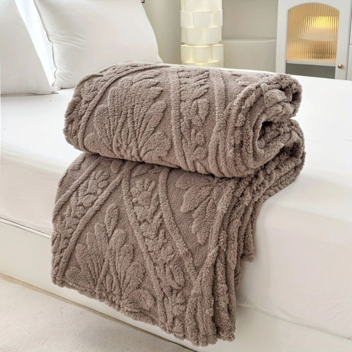 Cocoa Stone Embossed Plush Fleece Throw folded on a bed
