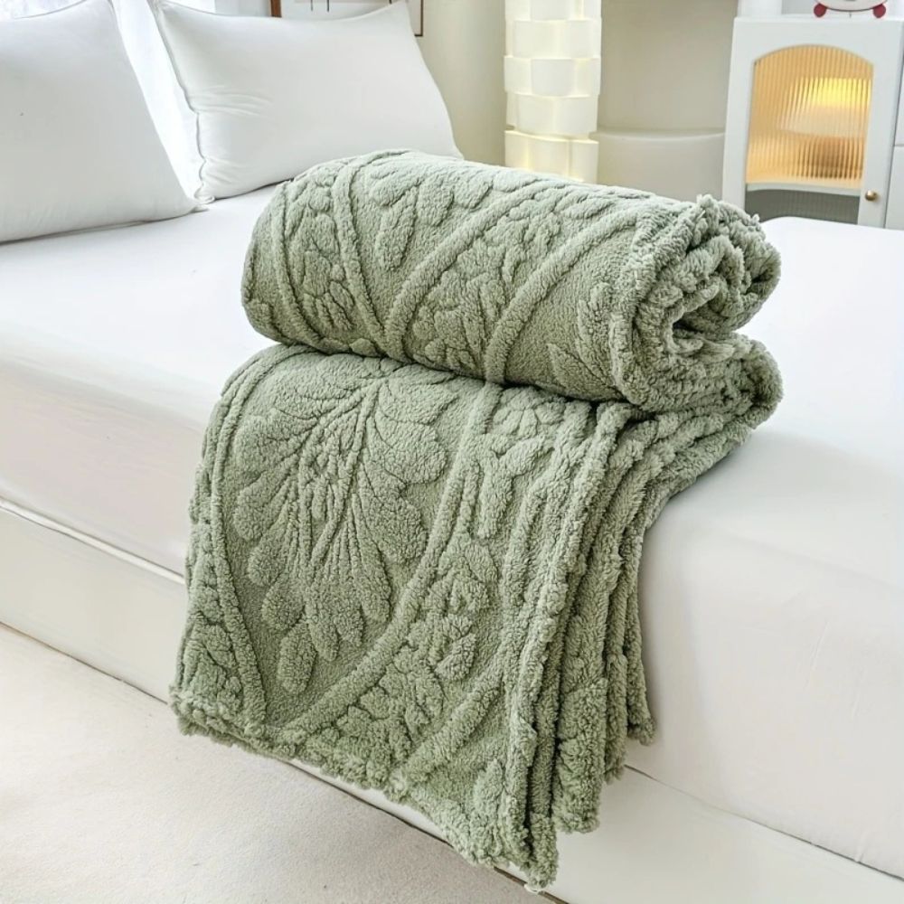Sage Leaf Embossed Plush Fleece Throw folded on a bed