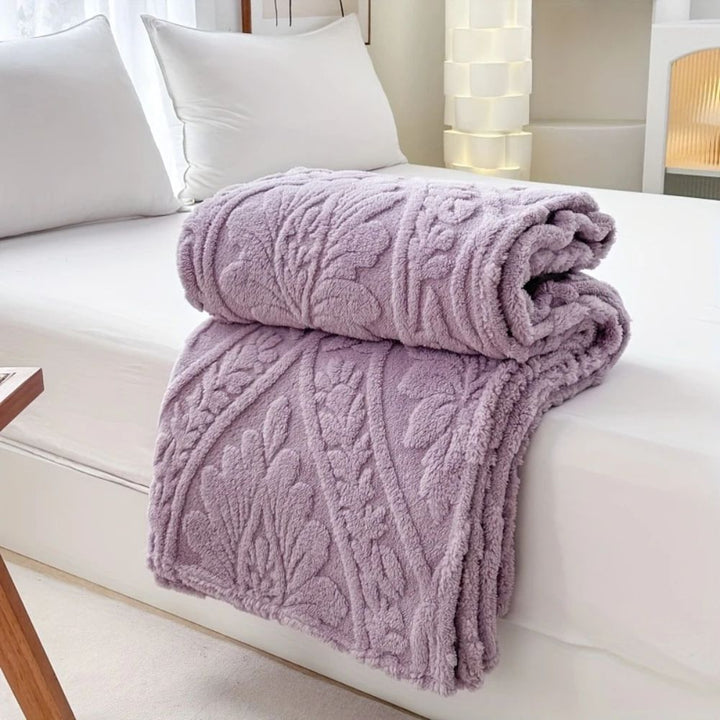 Lilac Mist Embossed Plush Fleece Throw folded on a bed