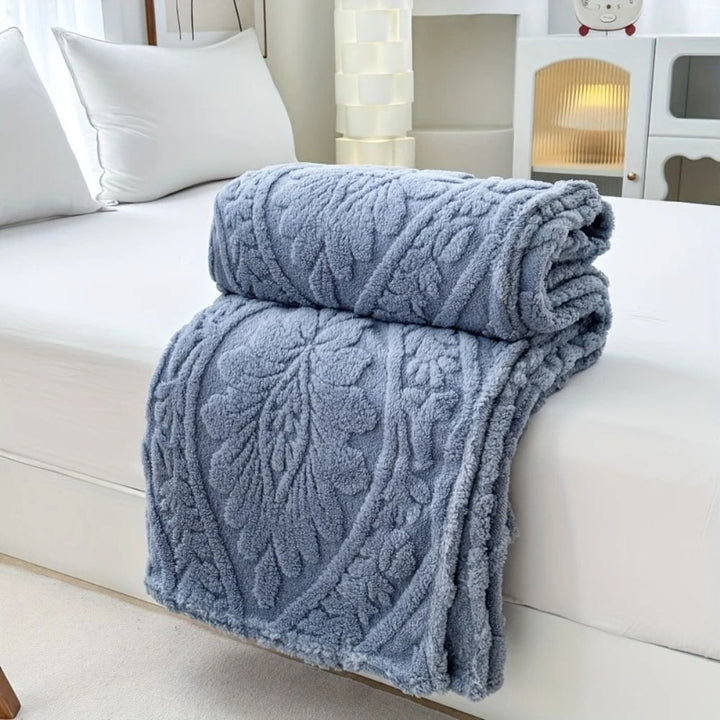 Storm Blue Embossed Plush Fleece Throw folded on a bed