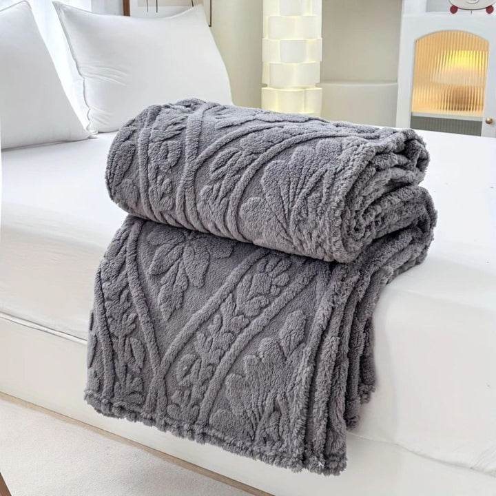 Slate Gray Embossed Plush Fleece Throw folded on a bed