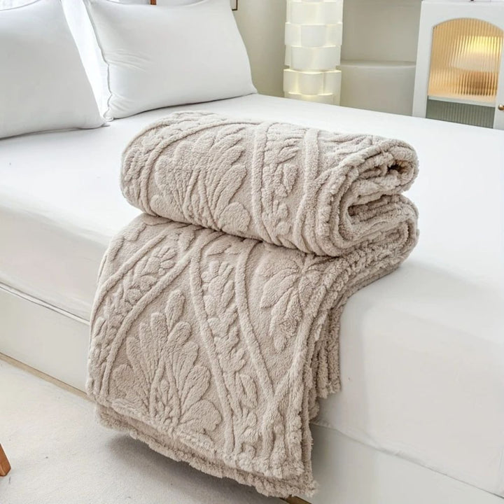 Sandstone Embossed Plush Fleece Throw folded on a bed