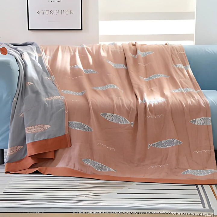 Soft Peach Fish Jacquard Cotton Gauze Blanket draped over sofa