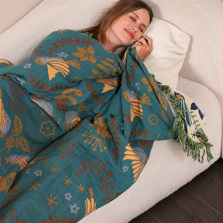 Nordic Bird Jacquard Cotton Throw wrapped around a resting model