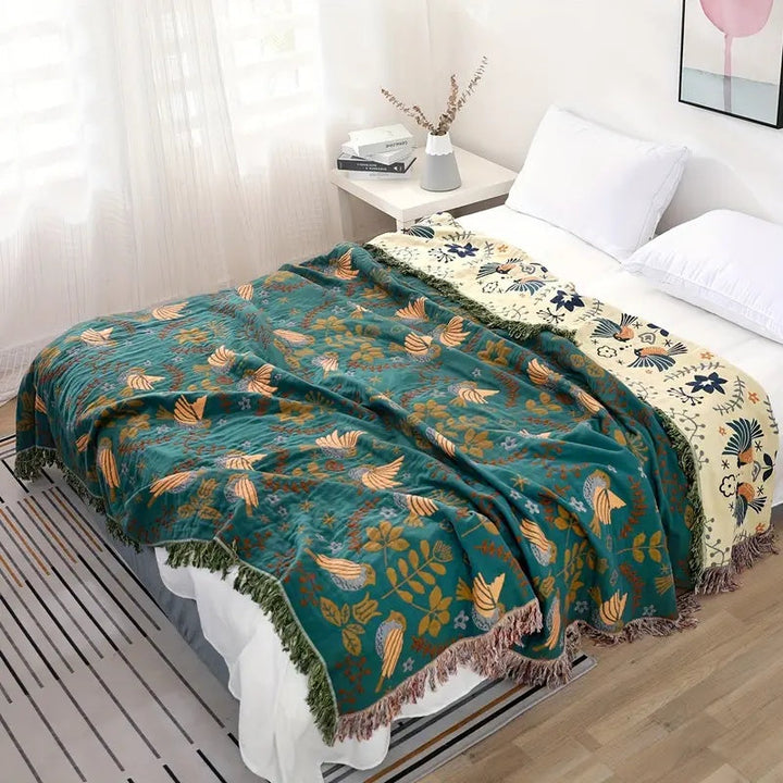 Nordic Bird Jacquard Cotton Throw folded at the end of a bed