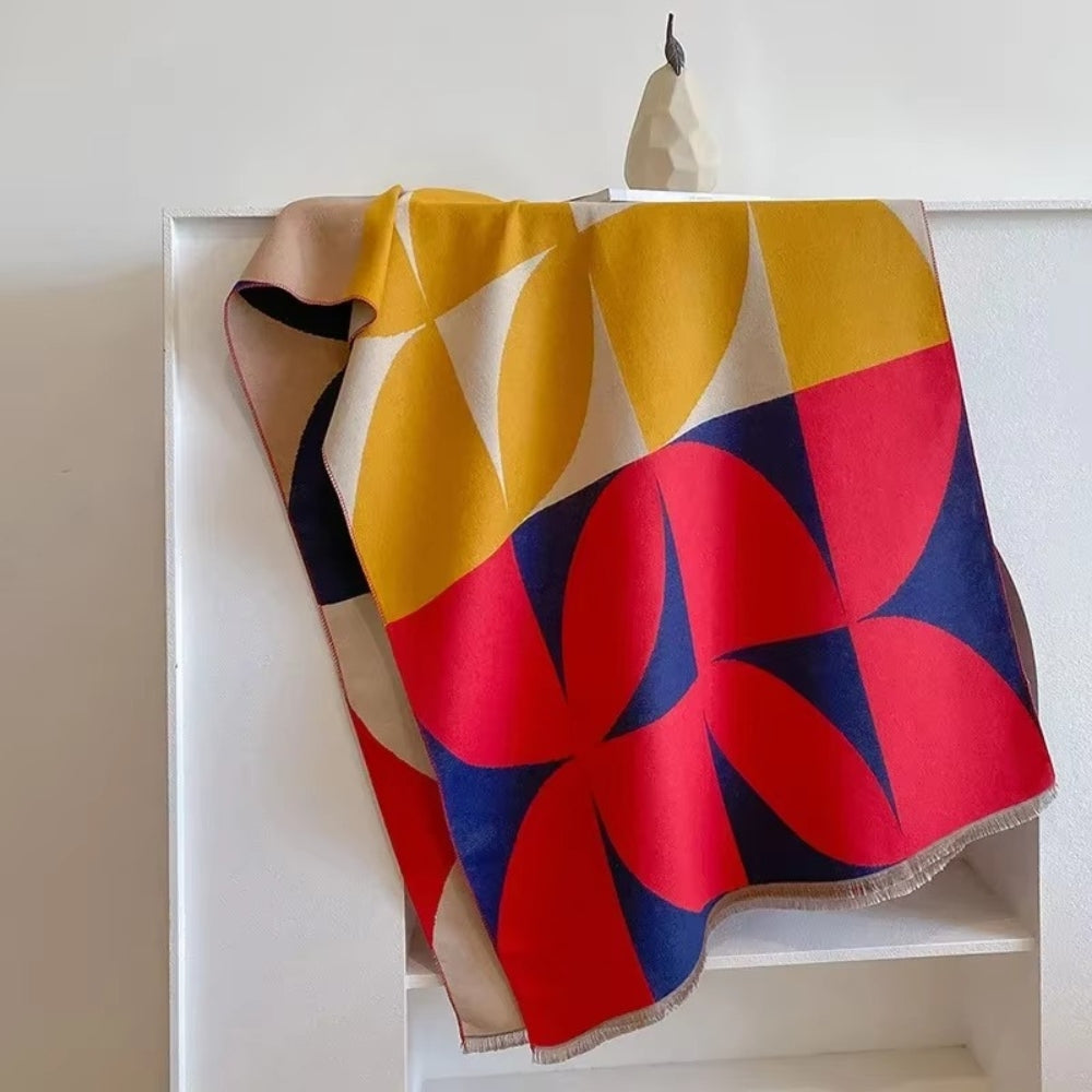 Red and yellow Reversible Geometric Poncho Scarf laid over chair
