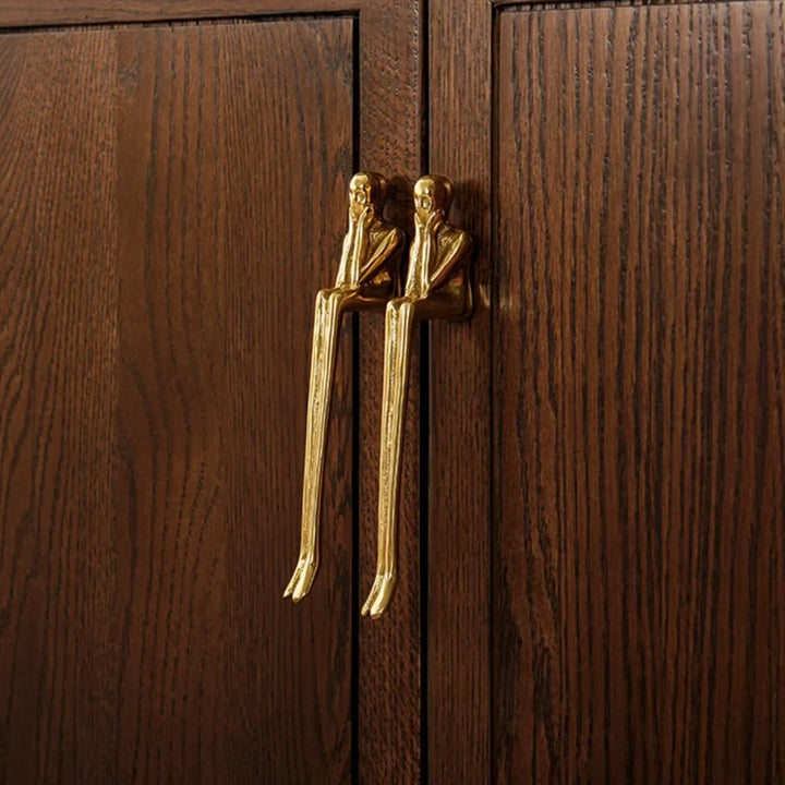 Gold Sculptural Figure Brass Cabinet Pulls on dark wood doors