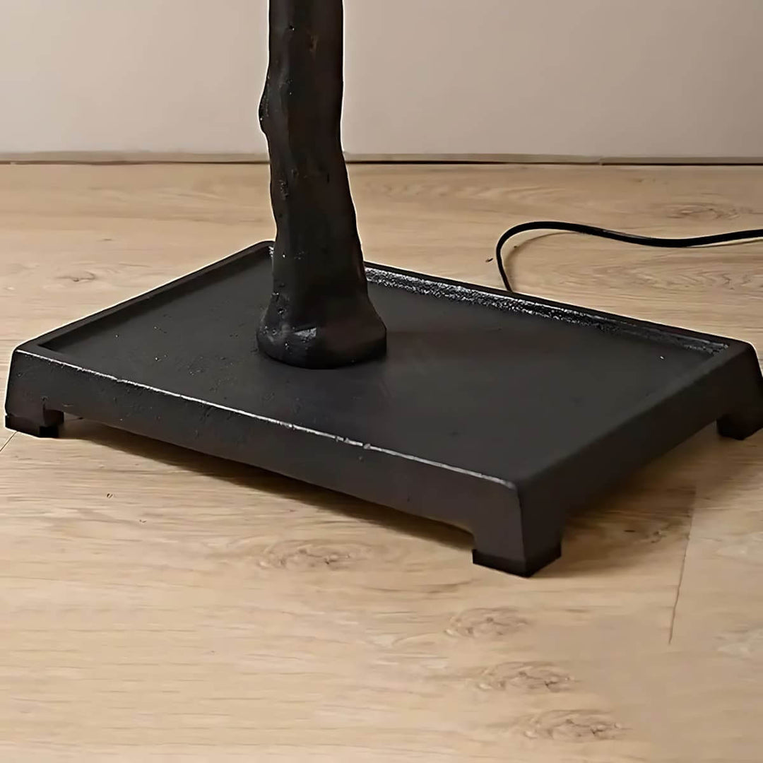 Close-up of the black square base and power cord on the Sivon Tree floor lamp.