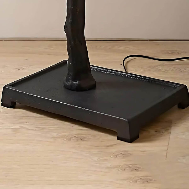 Close-up of the black square base and power cord on the Sivon Tree floor lamp.