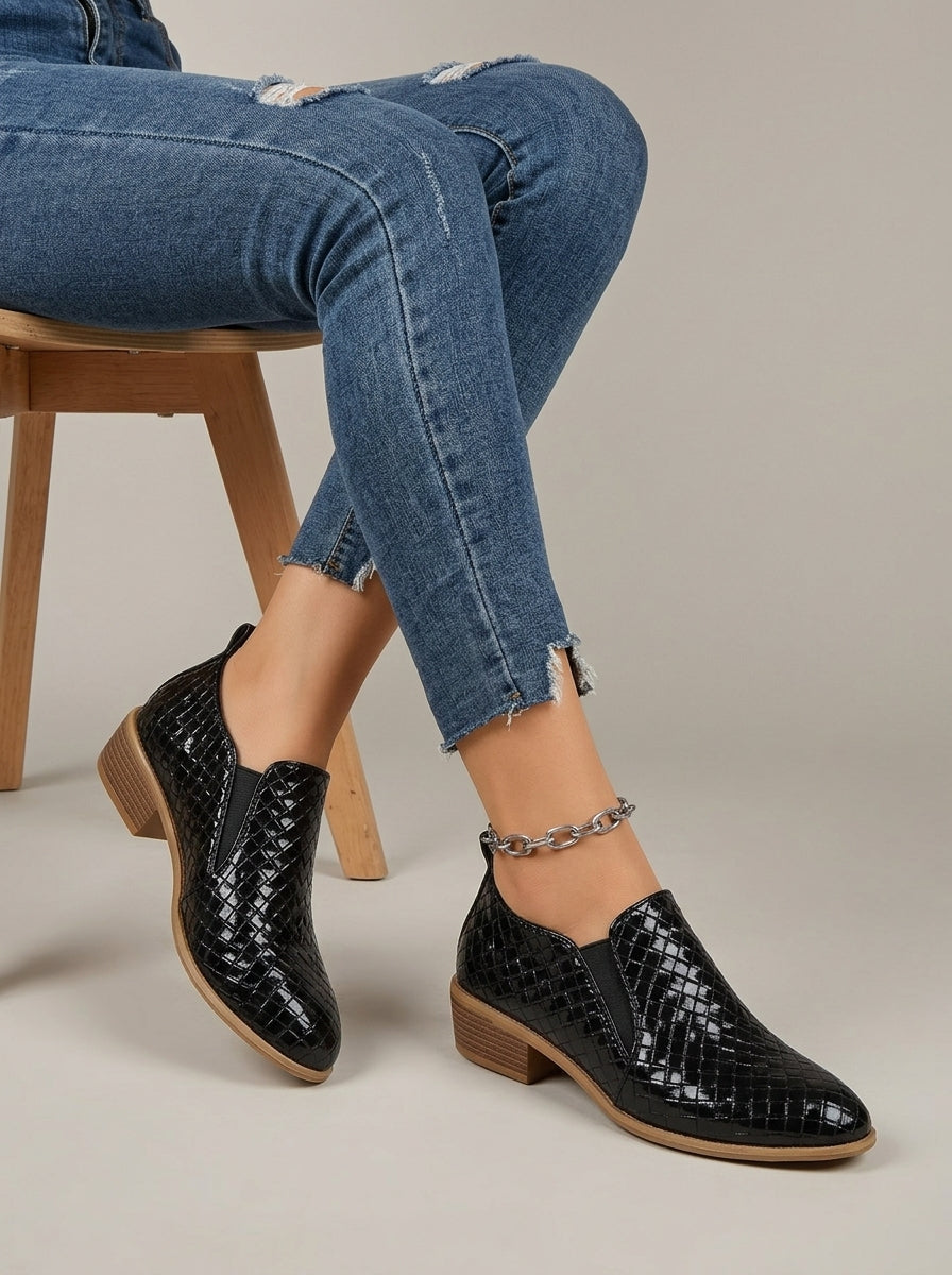 Black woven-texture slip-on ankle boots worn seated with jeans